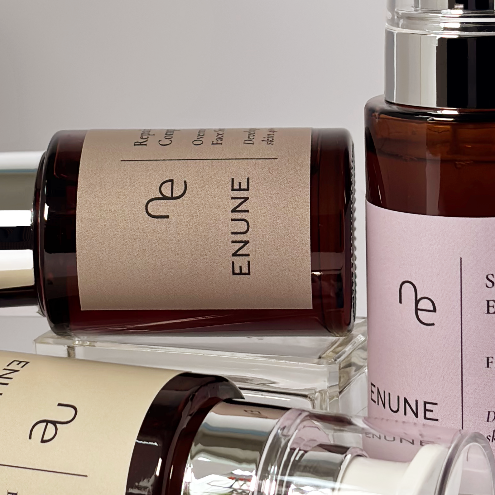 ENUNE Serum-Kollektion – mehrere Glasflaschen mit braunem und rosa Etikett, hochwertige Naturkosmetik für reife Haut ab 40
